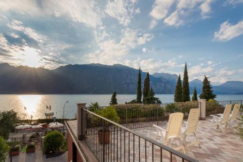 a patio with chairs and a view of a lake at Hotel Oasi Beach in Malcesine