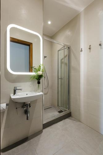a bathroom with a sink and a shower with a mirror at Two Pillows Boutique Hostel in Sliema