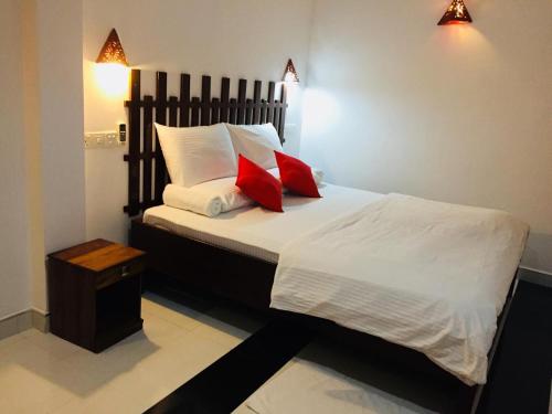 1 dormitorio con 1 cama con 2 almohadas rojas en Holaa Mirissa, en Mirissa