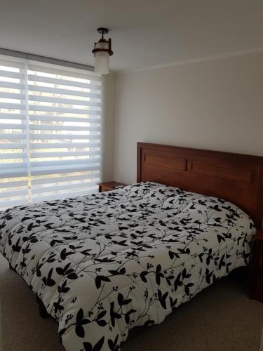 1 dormitorio con 1 cama con edredón blanco y negro en Condominio Parque Payllahue, en Pucón