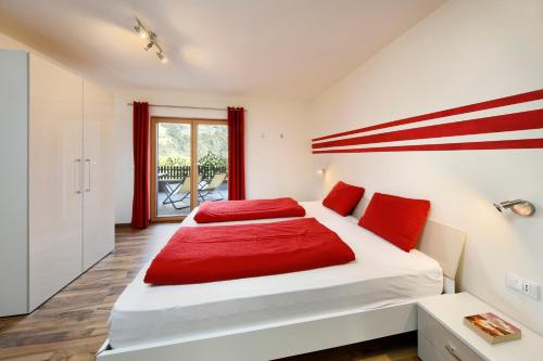 1 dormitorio con 1 cama grande con almohadas rojas en Bognerhof, en Rifiano