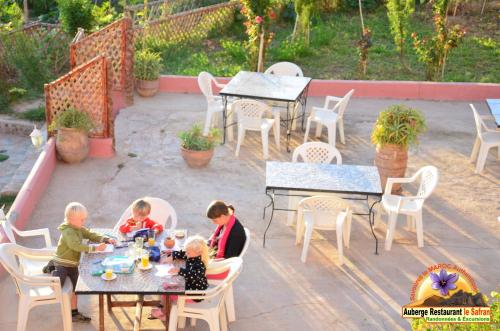 a woman and two children sitting at tables on a patio at Auberge Restaurant le Safran in Taliouine