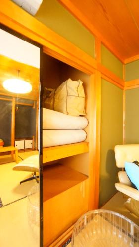 a room with a shelf with a stack of pillows at Tomato House Takayama in Takayama