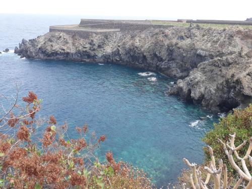 a body of water next to a rocky cliff at Mirador Playa San Marcos in Icod de los Vinos