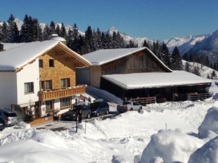 a house in the snow with cars parked in front at Haus Mondspitze in Bürserberg