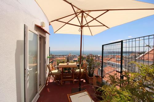 a balcony with a table and an umbrella at Estrela Penthouse - Amazing Views in Lisbon