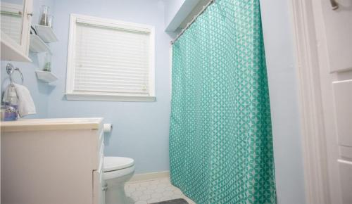 a bathroom with a shower with a green shower curtain at The Pineapple Lady 13min to Fort Benning in Columbus