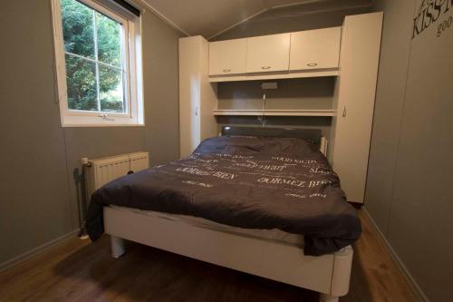 een bed in een kleine kamer met een raam bij Chalet Vakantie Wageningen Veluwe in Wageningen