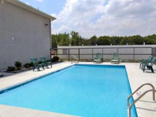 a large swimming pool with chairs and a building at Red Carpet Inn Macon East in Macon