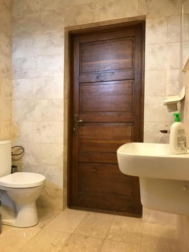 a bathroom with a wooden door and a toilet and a sink at Vila Blanca in Alexandru cel Bun