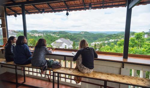 Cztery dziewczyny siedzące na ławce z widokiem na góry w obiekcie Tigon Dalat Hostel w mieście Da Lat