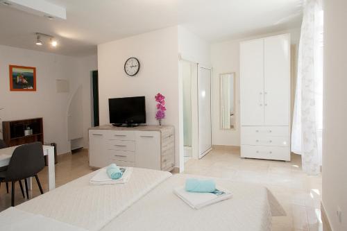 a white living room with a table and a tv at King's Garden Studio in Split