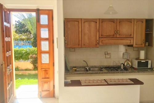 uma cozinha com armários de madeira, um lavatório e uma janela em The Garden em Tortolì