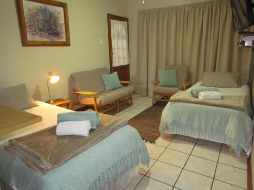 a bedroom with two beds and a couch and chairs at PureJoy Self-Catering Accommodation in Bloemfontein
