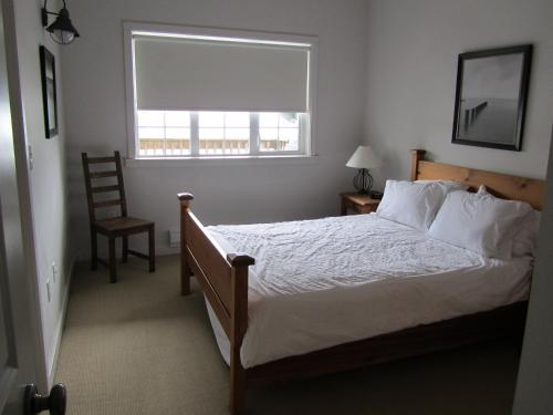 a bedroom with a bed and a window and a chair at 203 at Water's Edge in Ucluelet