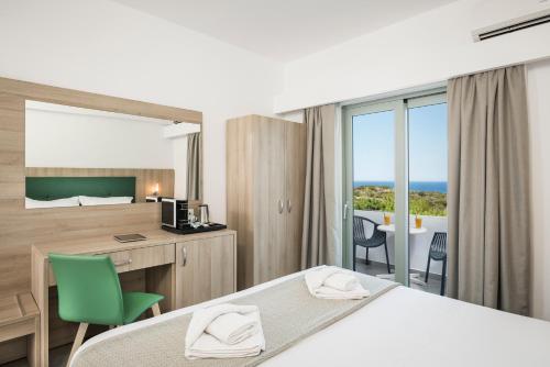 a hotel room with a bed and a desk and a window at Glykeria Hotel in Elafonisi