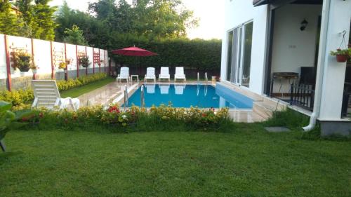 a backyard with a swimming pool with chairs and an umbrella at Villa kardelen in Sapanca