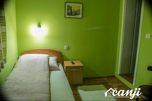 a small green bedroom with a bed and a night stand at Pansion Čanji in Bački Petrovac