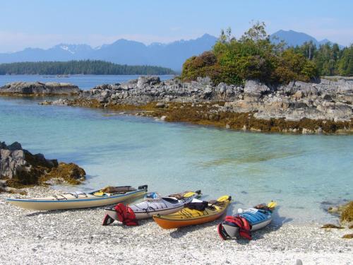 three kayaks on a beach next to a body of water at 203 at Water's Edge in Ucluelet