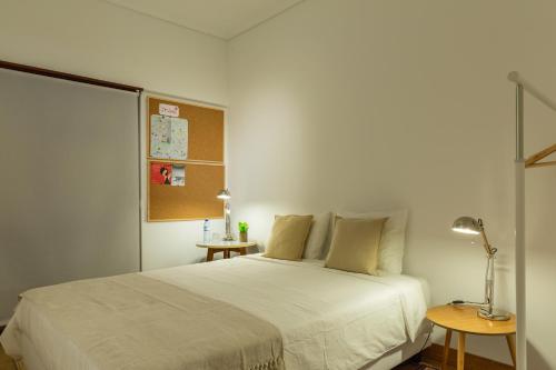 a bedroom with a white bed and two tables at Alface Room in Lisbon