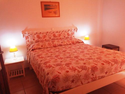 a bedroom with a bed with a red bedspread and two lamps at Maio Vacanze in Vila do Porto