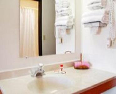 Un mostrador de baño con un lavabo y un espejo. en Westwood Inn & Suites - Kimball, en Kimball