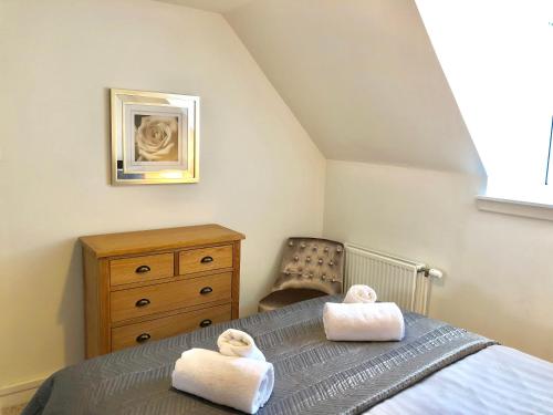 a bedroom with two towels on a bed with a chair at City Centre Cottage in Inverness