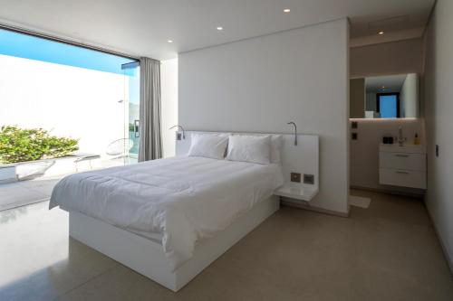 ein Schlafzimmer mit einem weißen Bett und einem großen Fenster in der Unterkunft Livega House in Windhoek