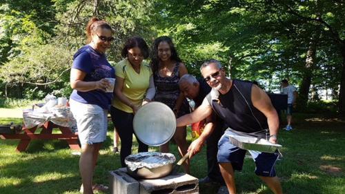 a group of people standing around a grill at Catskill Motor Court in Catskill