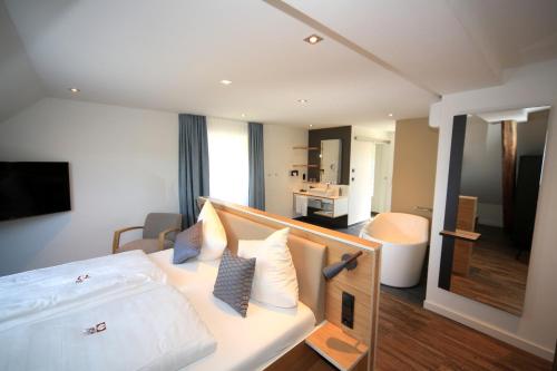 a bedroom with a white bed and a living room at Hotel Halfenstube & Villa Spa 1894 in Senheim