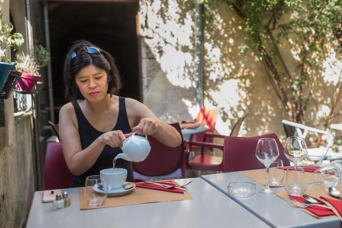une femme est assise à une table avec une tasse dans l'établissement Les suites de Peyrat, à Pézenas