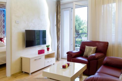 a living room with a couch and a chair and a tv at Apartman Boska Lux in Subotica