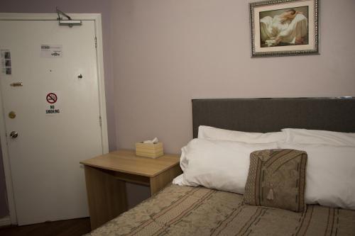 a bedroom with a bed with a table and a picture on the wall at Saint Lawrence Residences and Suites in Toronto