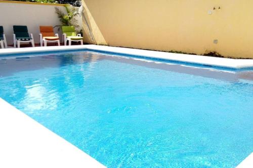 a large blue swimming pool with chairs next to a building at Casa Coral Cozumel in Cozumel