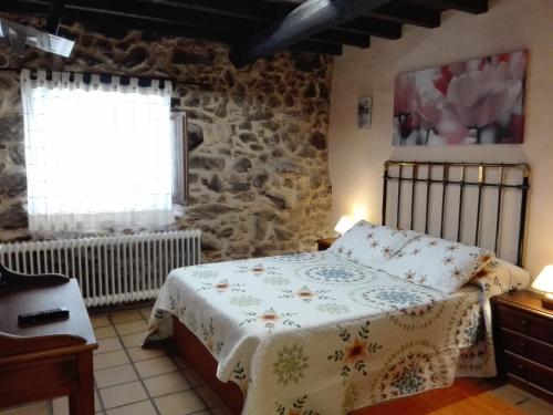 a bedroom with a bed and a stone wall at Hotel La Casa Chacinera in Candelario