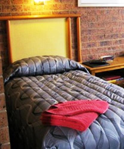 a bed with a red pillow on top of it at The Wayfarer Motel in Muswellbrook
