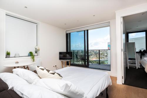 a bedroom with a large white bed and large windows at Brand New Auckland Apartment in Auckland