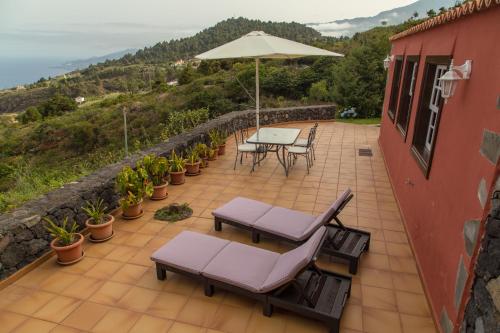 un patio con mesa, sillas y sombrilla en Country house Santa Lucia, en Puntallana