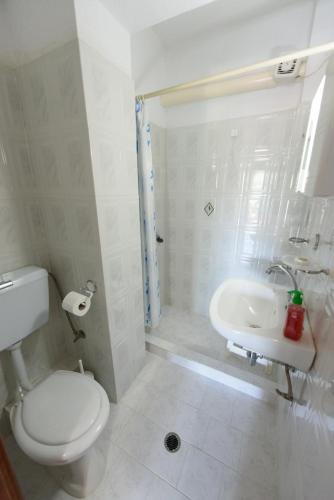 a white bathroom with a toilet and a sink at Villa Mara in Panormos Skopelos