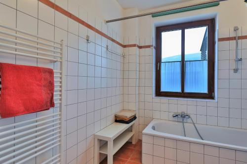 a white tiled bathroom with a tub and a window at Ferienwohnungen Gritzner in Tröpolach