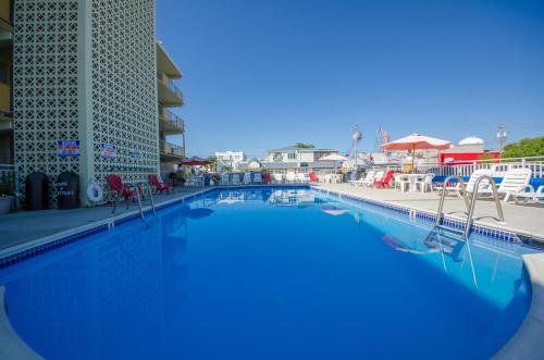 a swimming pool at a resort with chairs and tables at Landmark Motel in Wildwood
