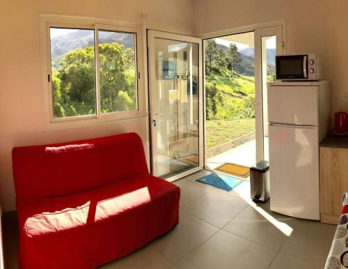 ein Wohnzimmer mit einem roten Stuhl und einem Kühlschrank in der Unterkunft Gite Le Panoramique in Dumbéa