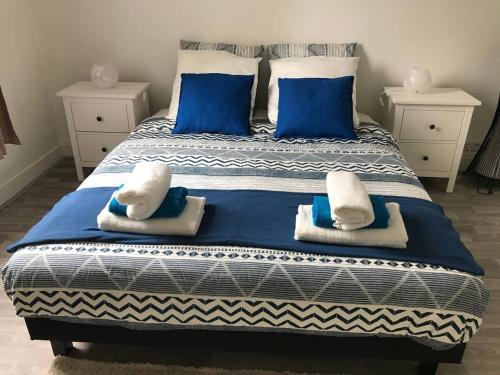 a bed with blue and white sheets and blue pillows at Grand F3 Paris Stade de France & La Villette, 6 pers - Metro 7 in Aubervilliers