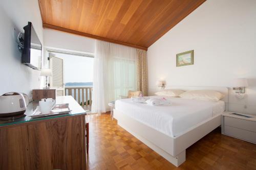 Schlafzimmer mit einem weißen Bett und einem TV in der Unterkunft Apartmens Villa Antonio 88 in Brela
