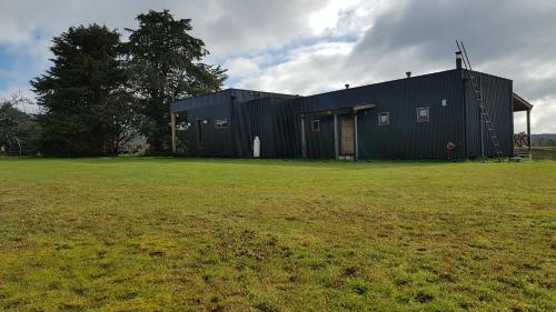a black building with a grass field in front of it at Hostal Boutique Los Arrayanes in Castro