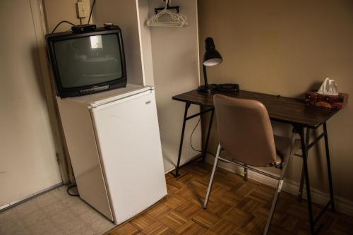 a room with a table and a television on top of a refrigerator at Saint Lawrence Residences and Suites in Toronto