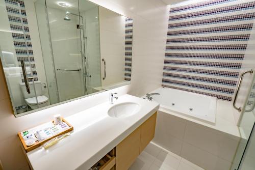 a bathroom with a sink and a tub and a mirror at Eusta Motel in Taichung