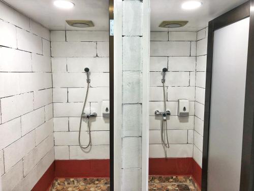 La salle de bains est pourvue d'une douche et de carrelage blanc. dans l'établissement Kea Garden Mini Chalet, à Cameron Highlands