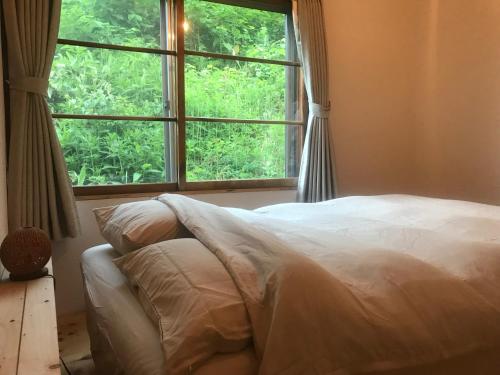 ein Schlafzimmer mit einem Bett und einem großen Fenster in der Unterkunft NORD house in Iwamizawa