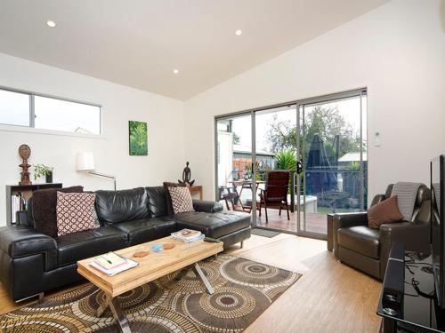 a living room with a black leather couch and a table at Seagrass Villas Normanville in Normanville